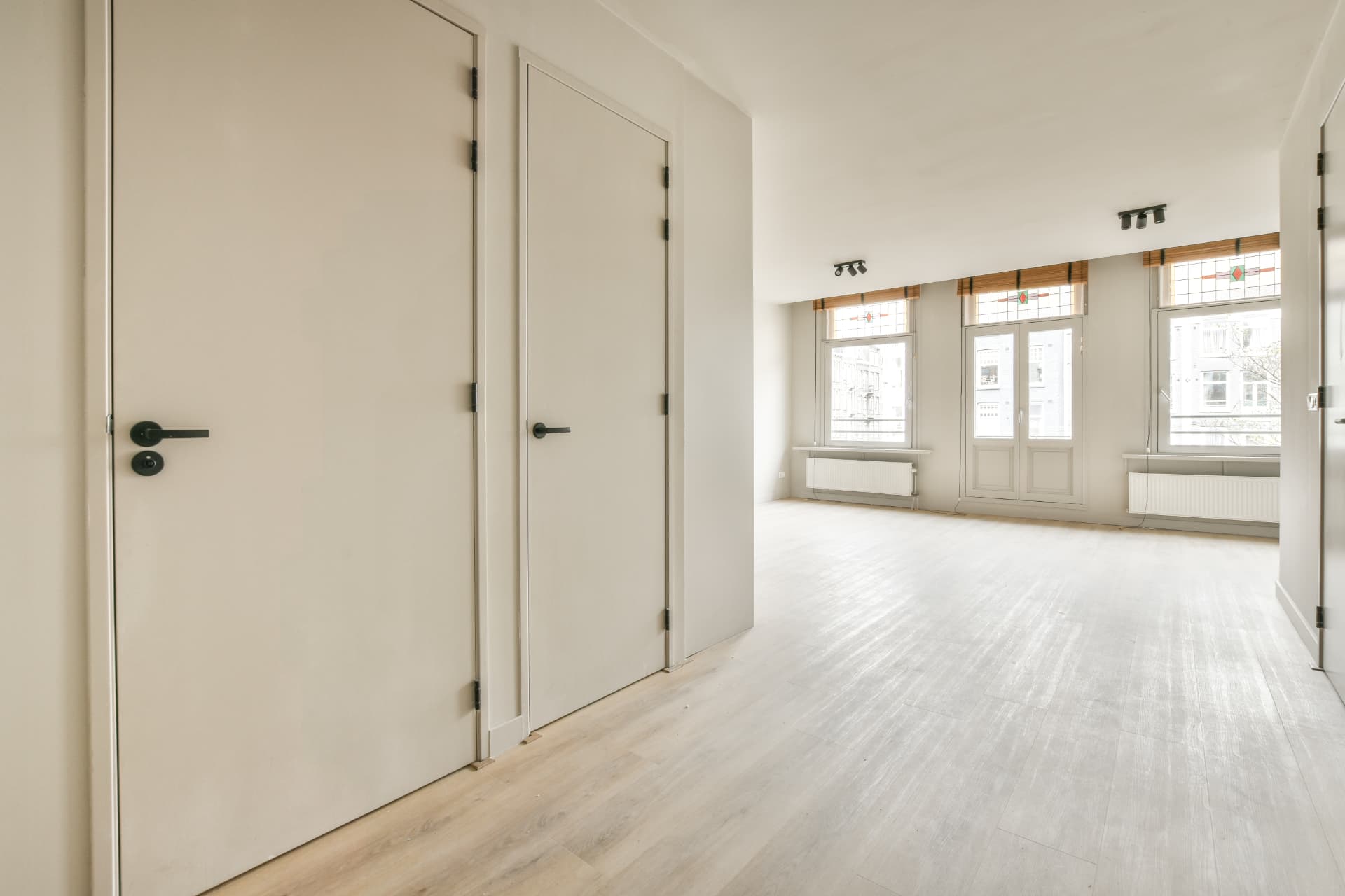 Bright empty apartment with white walls and clean wooden flooring ready for handover